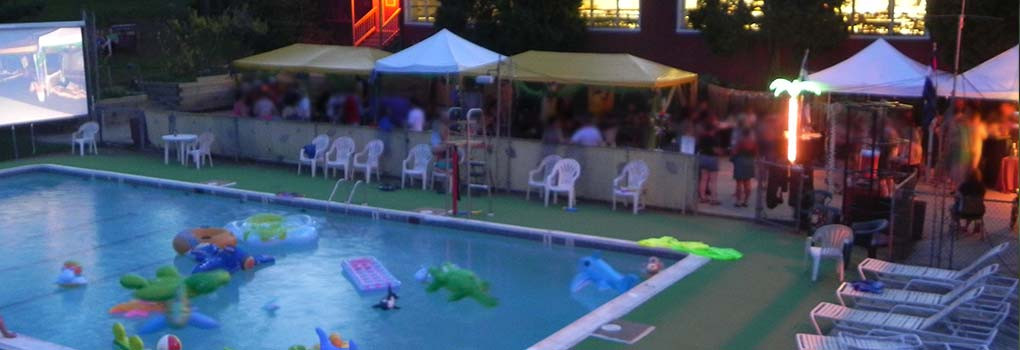 an evening pool party, with lots of inflatable toys in the pool and some very blurry people enjoying cocktails