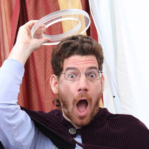 bearded man with glasses holde a halo over his head and makes a silly face