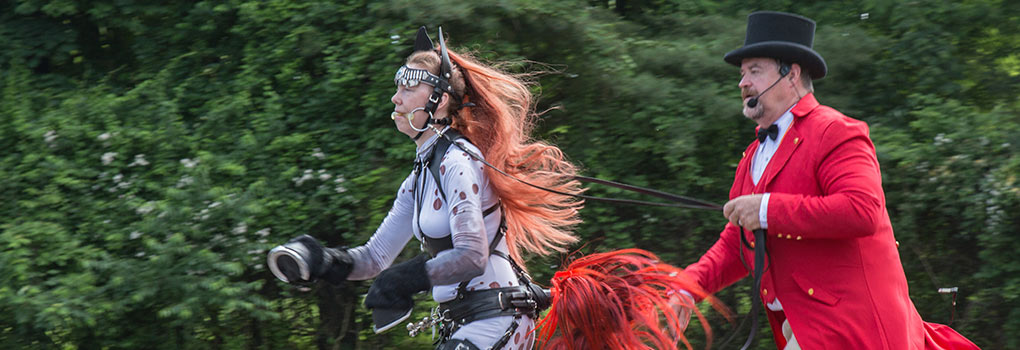 a man in a red coat and top hat handling an appaloosan pony player