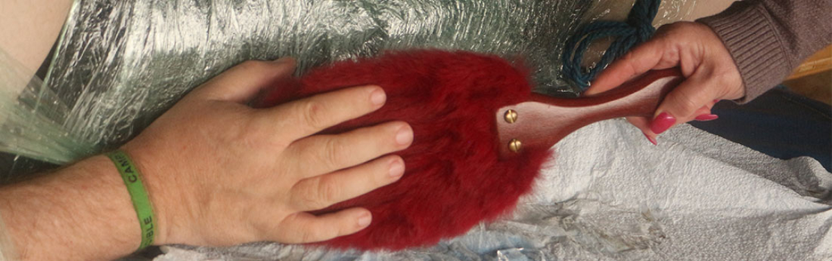 a hand pets a fur paddle held by another hand with red nails